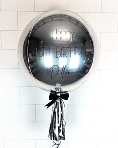 COLLECTION ONLY - Silver Orbz Balloon, Personalised with a Black Message Dressed with Tassel, Bow & Weight